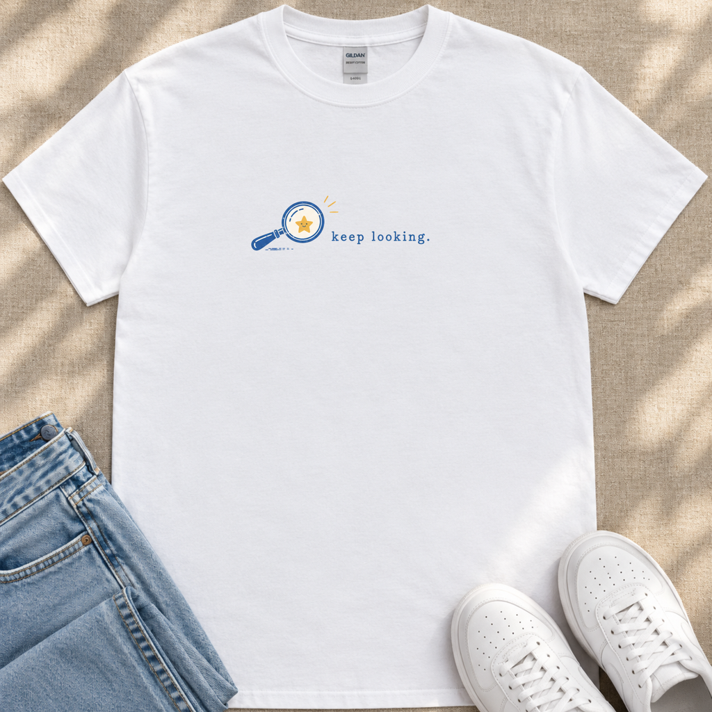 a white t-shirt with a graphic design, a pair of blue jeans, and a pair of white sneakers, all laid out on a surface.