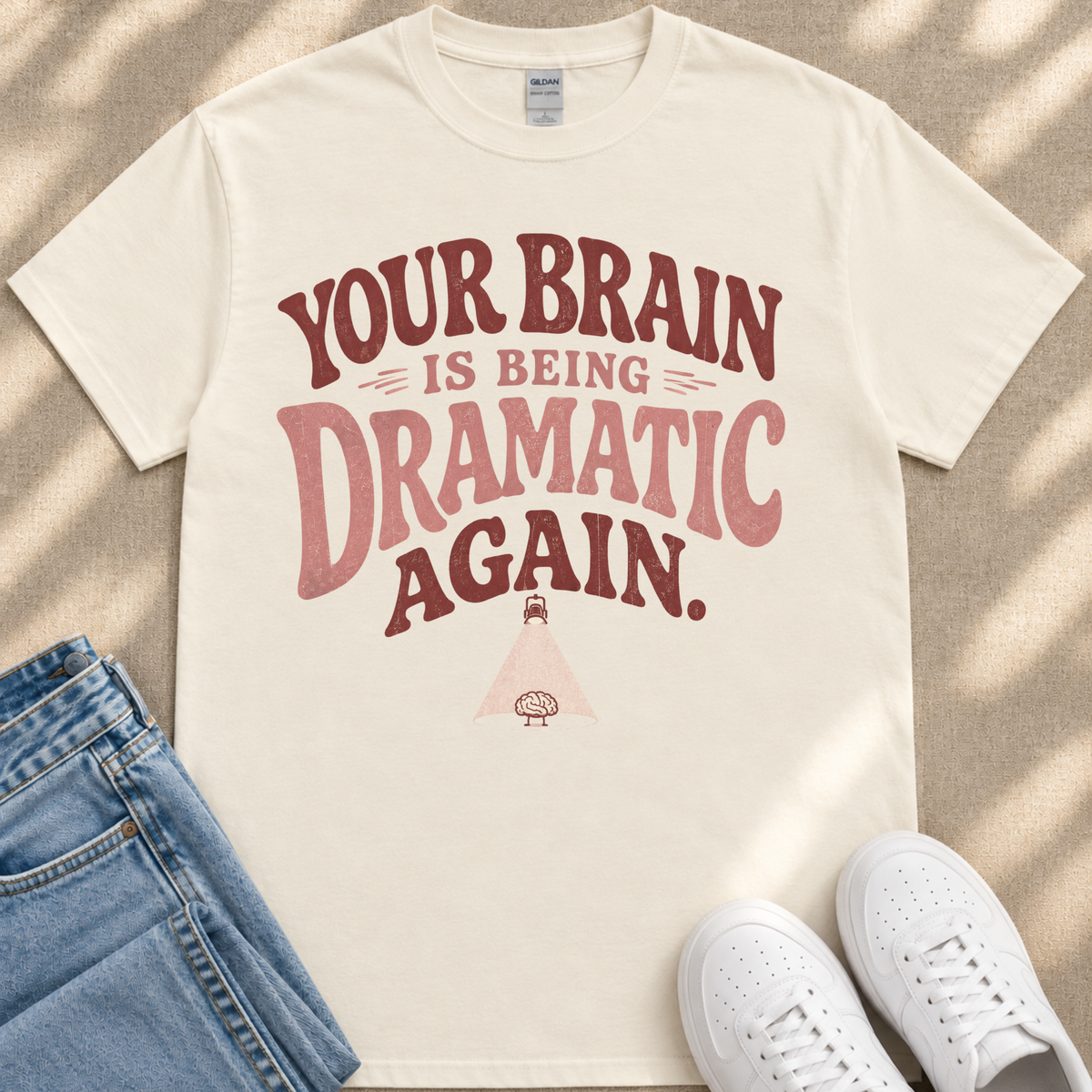 A white t-shirt with a humorous text printed on it, along with a pair of jeans and white sneakers.