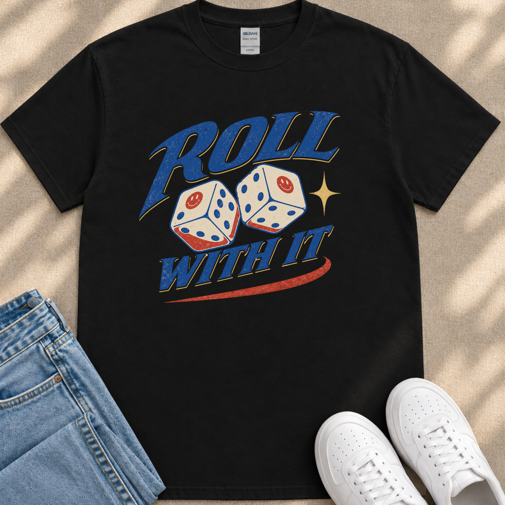 A black t-shirt with a graphic design featuring two dice with a smiley face, along with the text "Roll with it" and a red and blue stripe. The t-shirt is placed next to a pair of jeans and white sneakers.