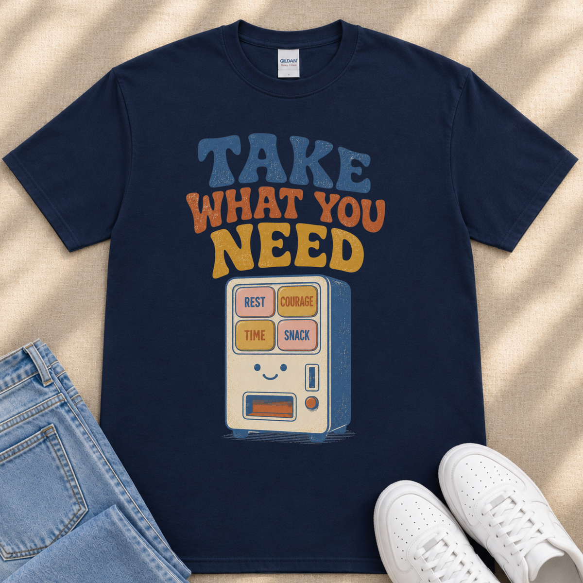 A navy blue t-shirt with a graphic design featuring a vending machine with the text "TAKE WHAT YOU NEED" printed on it.