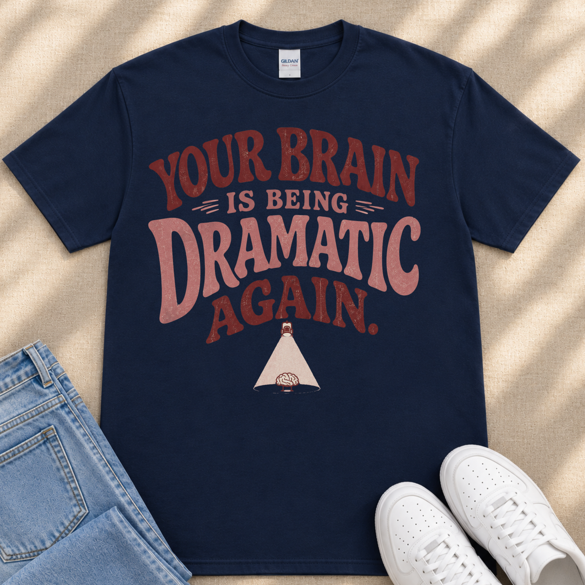 A navy blue t-shirt with a humorous text printed on it, along with a pair of jeans and white sneakers.