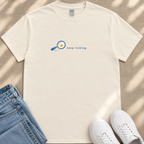 a white t-shirt with a graphic design, a pair of blue jeans, and a pair of white sneakers, all laid out on a beige surface.