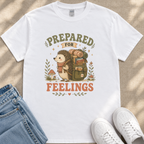 A white t-shirt with a graphic design depicting a hedgehog carrying a backpack and the text "PREPARED FOR FEELINGS" printed on it.