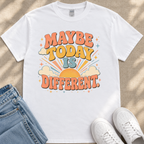 A white t-shirt with a colorful graphic design that says "MAYBE TODAY IS DIFFERENT" along with a sun and clouds design.